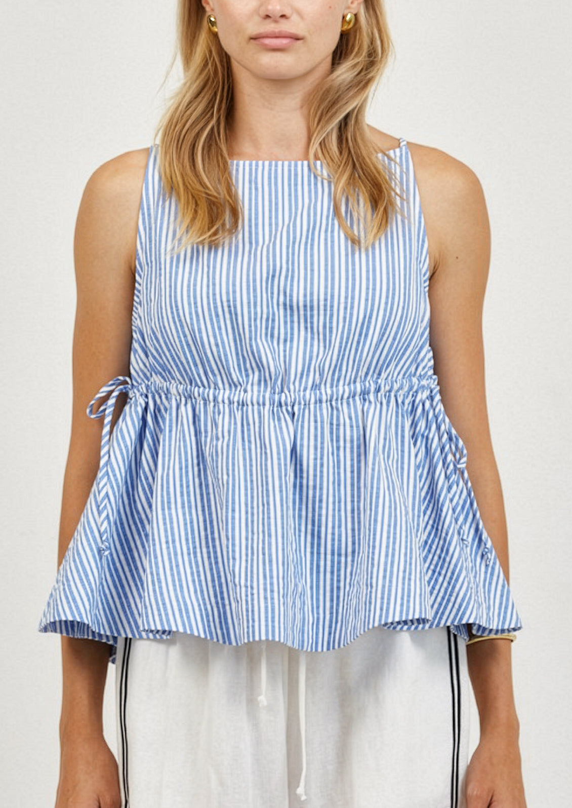 Woman wearing a blue and white striped sleeveless top against a plain background