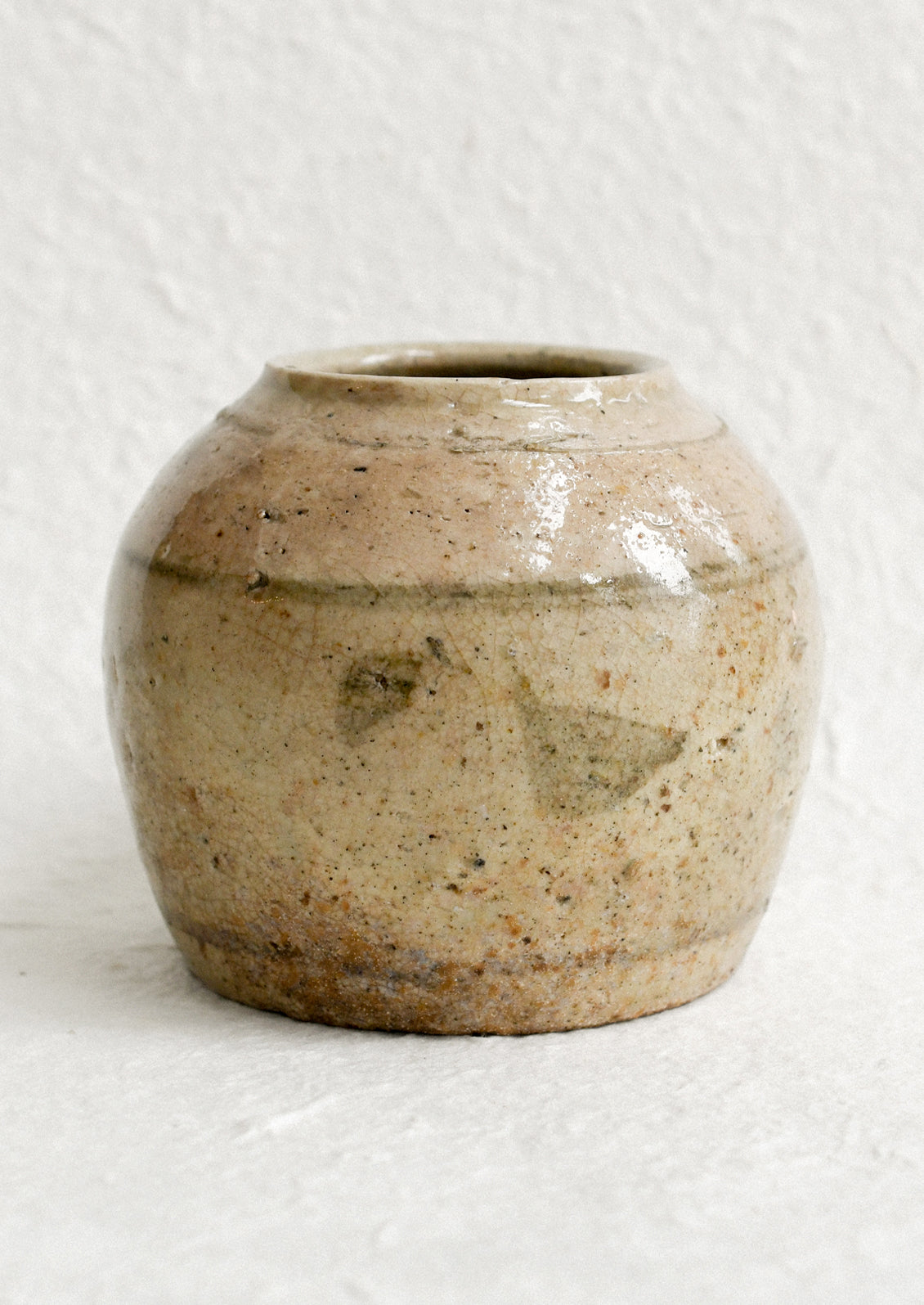 A small ironstone antique jar in greyish brown with heavy patina and soft stripe pattern.