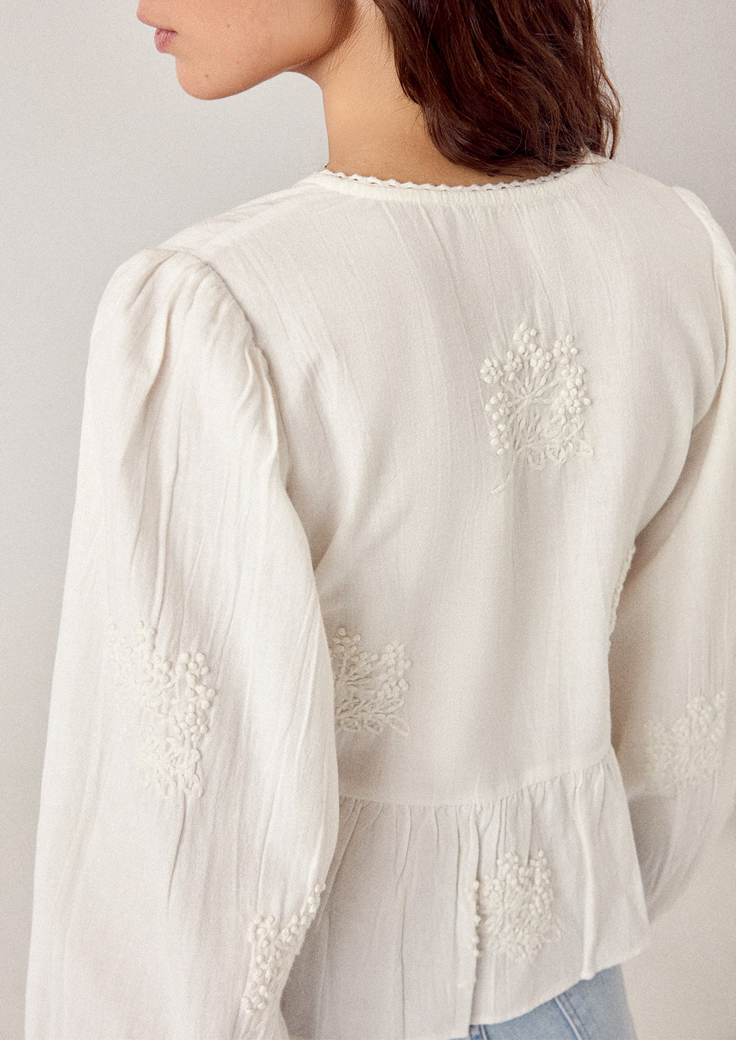 White blouse with floral embroidery on a plain background