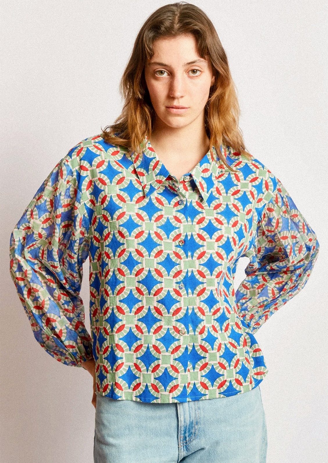 A woman wearing a shirt in blue, red and green geometric block print.
