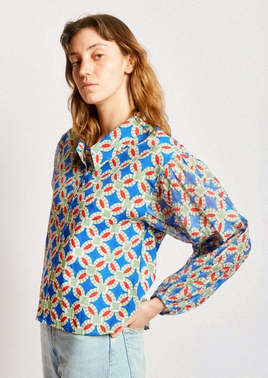 A woman wearing a shirt in blue, red and green geometric block print.
