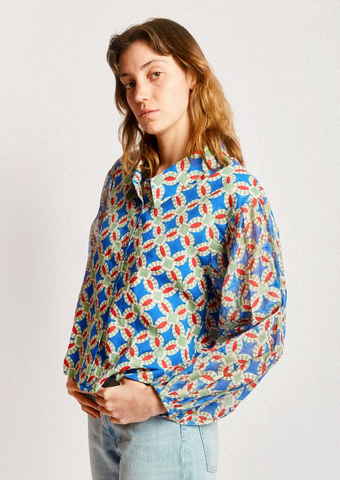 A woman wearing a shirt in blue, red and green geometric block print.
