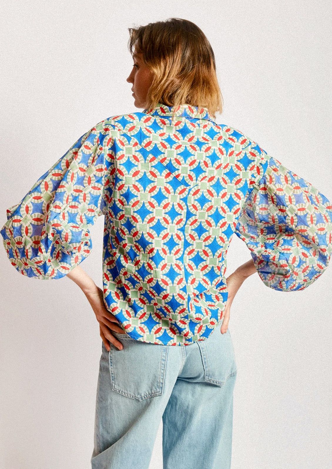 A woman wearing a shirt in blue, red and green geometric block print.