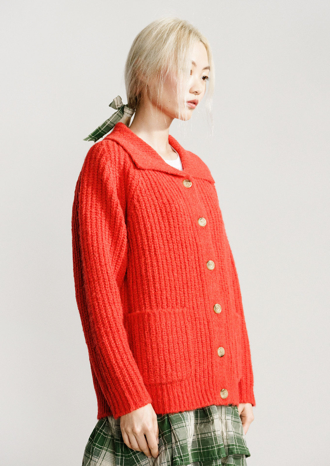 A woman wearing a red-orange knit cardigan sweater.
