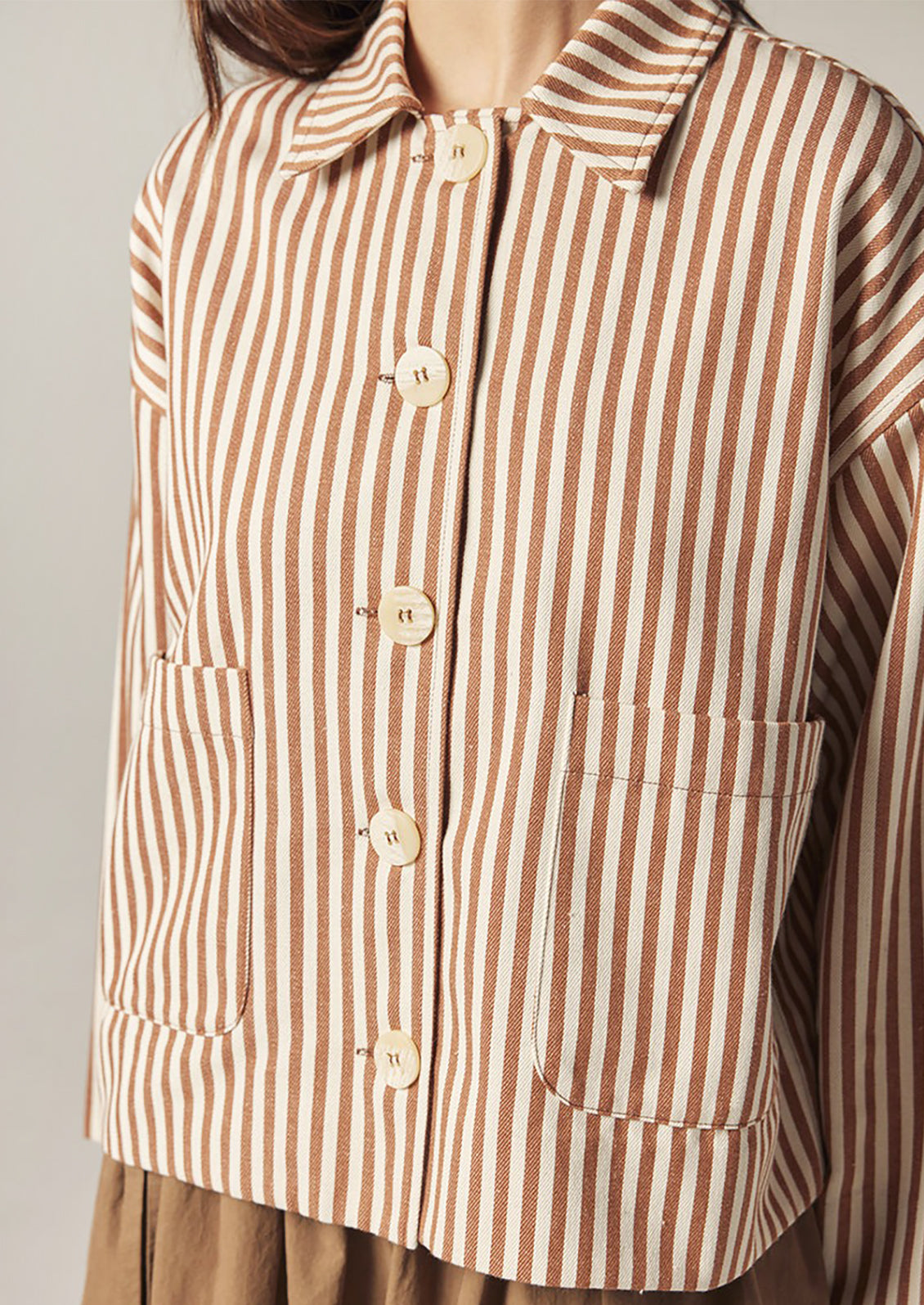 Brown and white striped shirt with buttons on a plain background