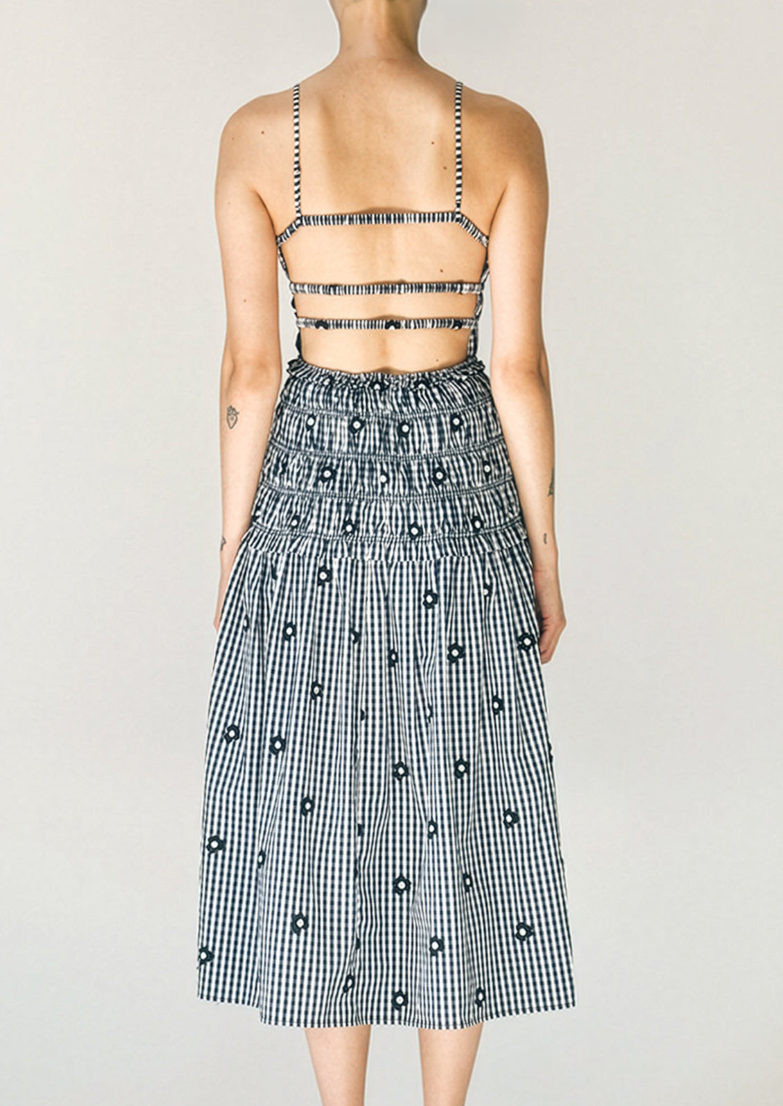 Person wearing a black and white checkered dress with floral details on a plain background