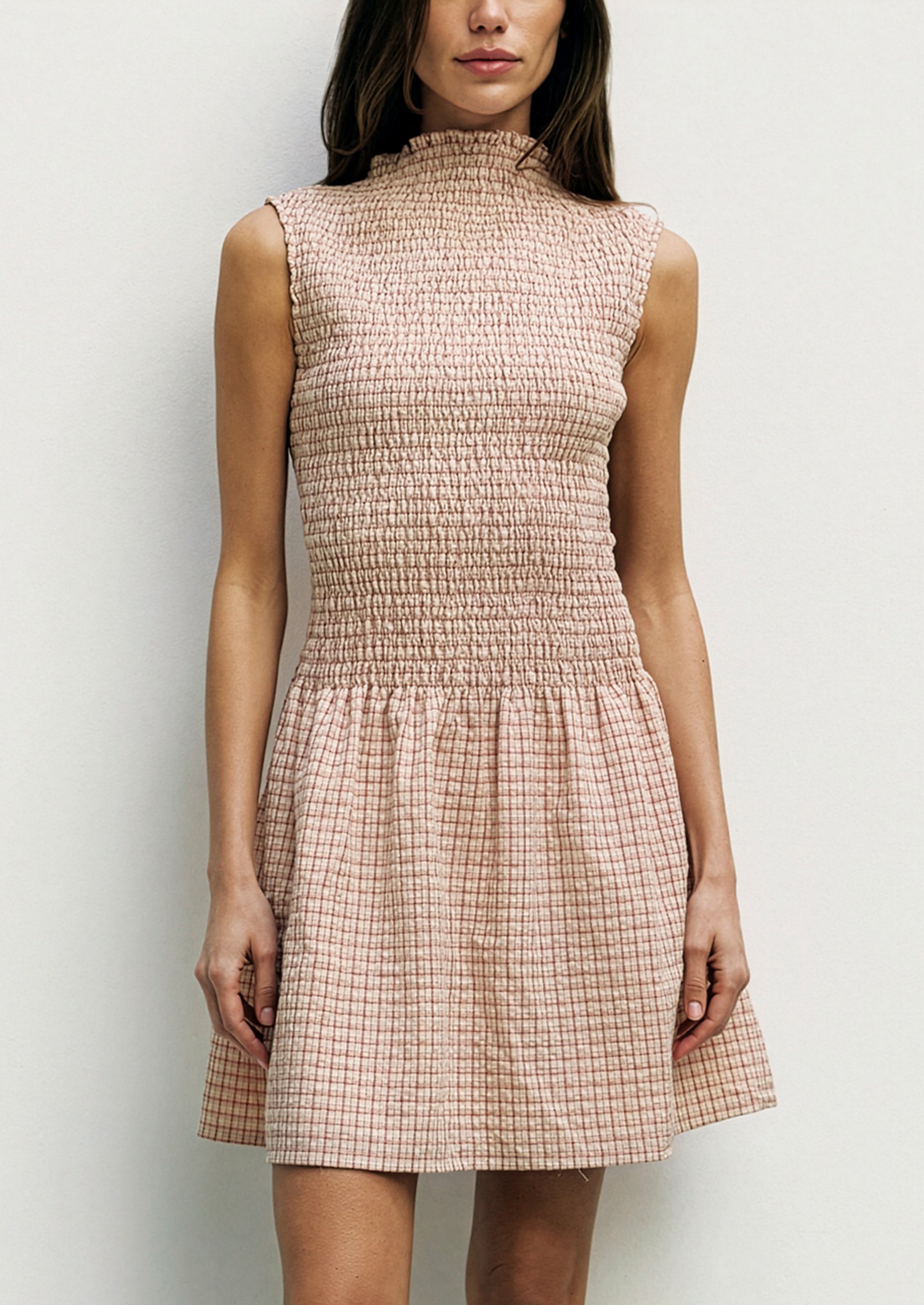 Woman wearing a checkered dress against a plain background