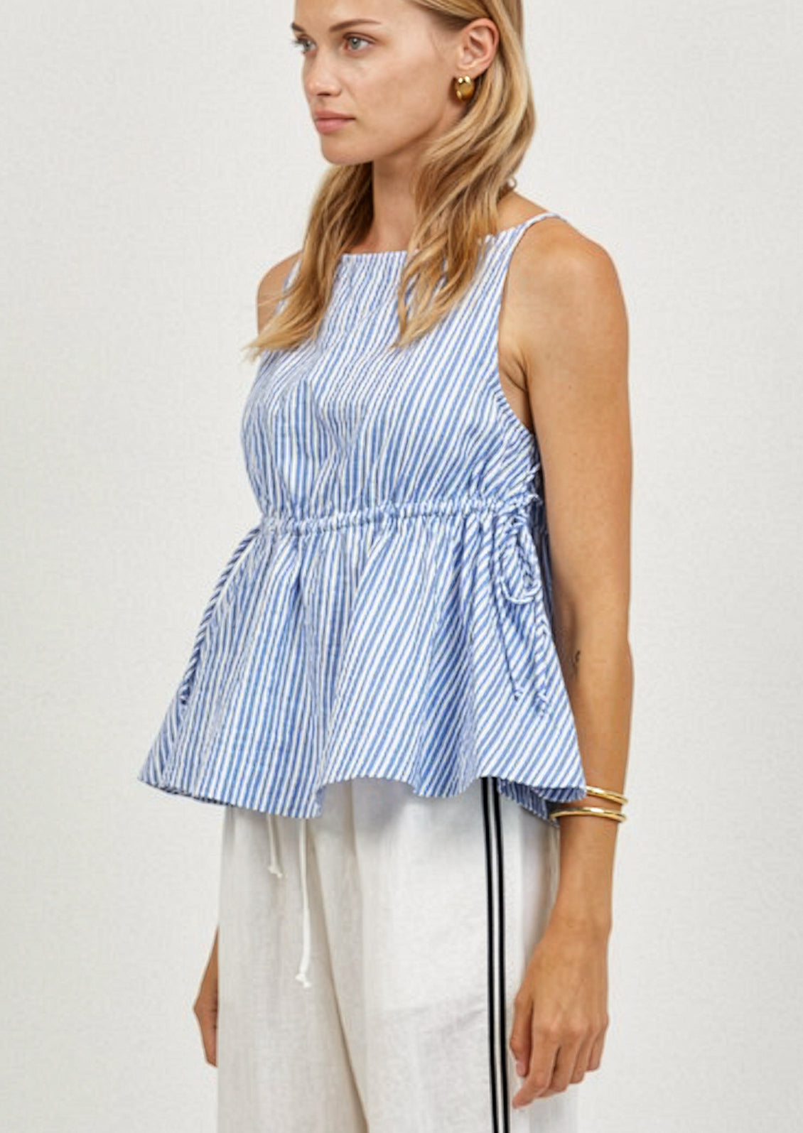 Woman wearing a blue and white striped sleeveless top with a plain background