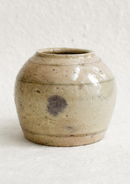 A small ironstone antique jar in greyish brown with heavy patina and soft stripe pattern.