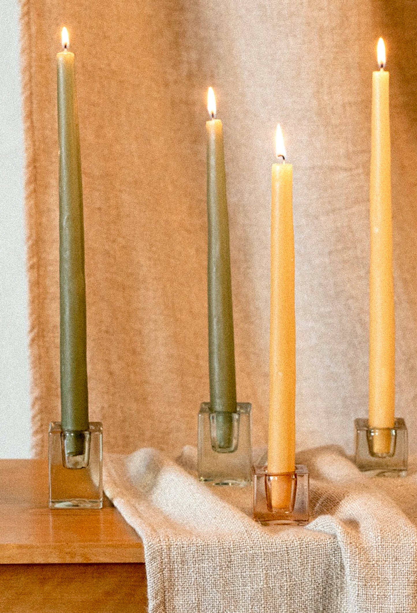 Slab glass candleholders in assorted colors, holding taper candles.