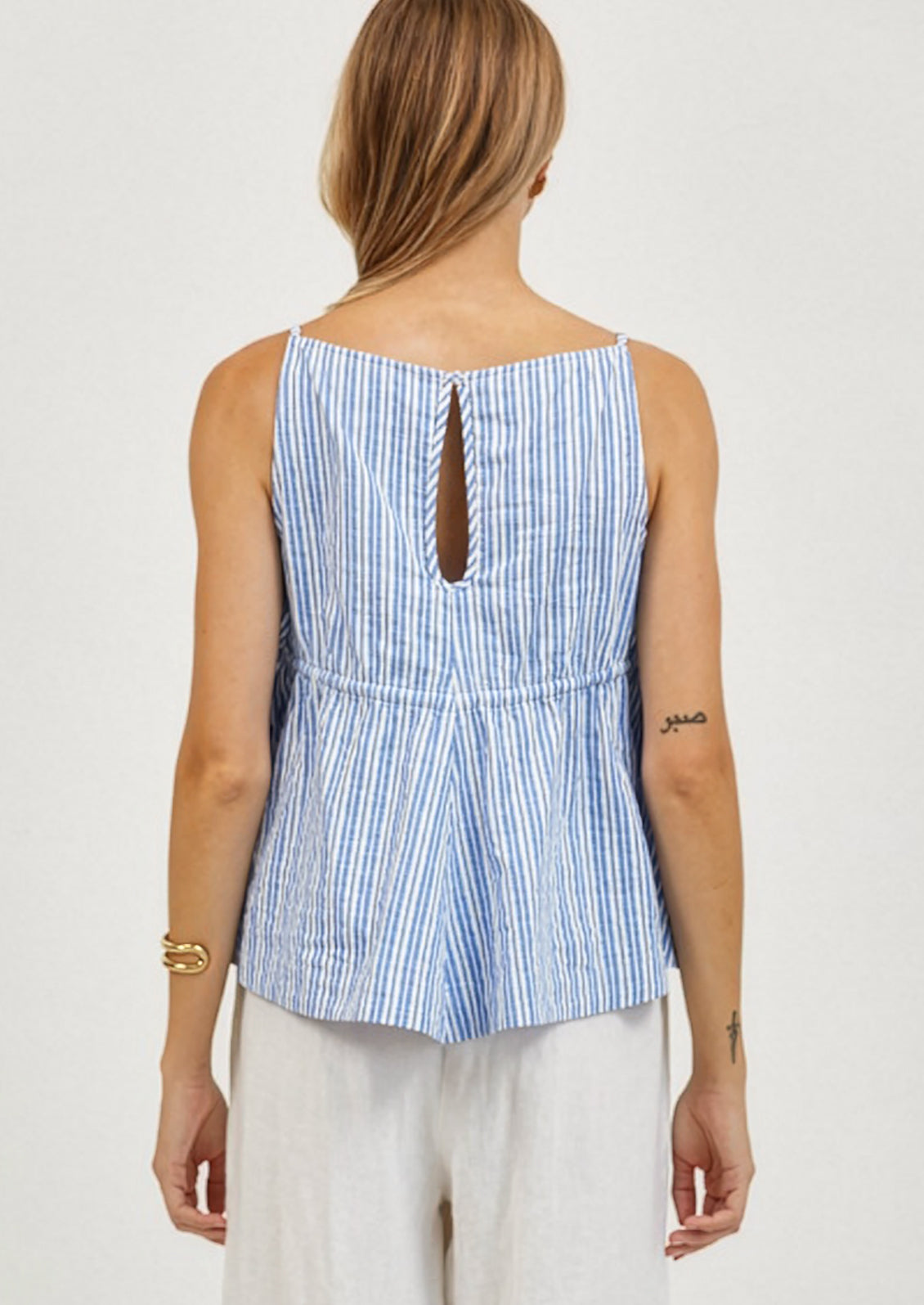 Woman wearing a blue and white striped sleeveless top on a plain background