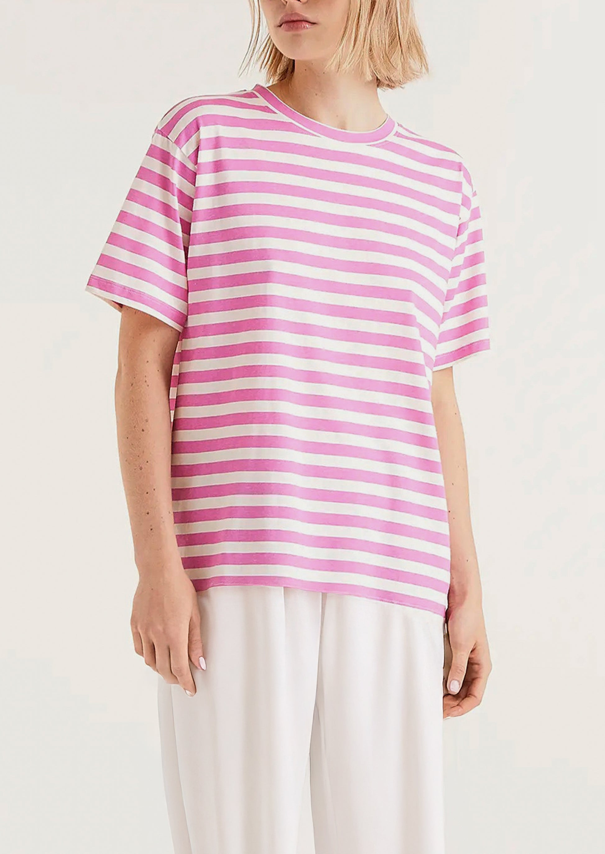 A woman wearing a striped short sleeve t-shirt in pink and white.