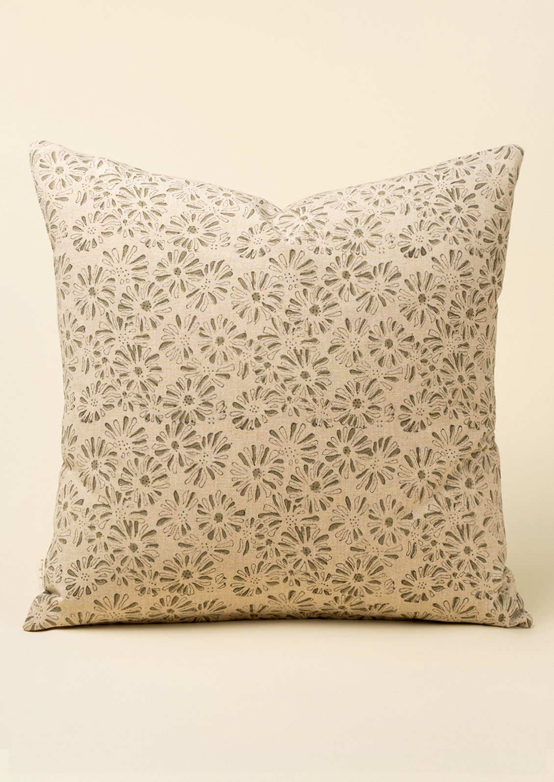 A square throw pillow with a beige and brown floral lace-like pattern, set against a solid cream background.