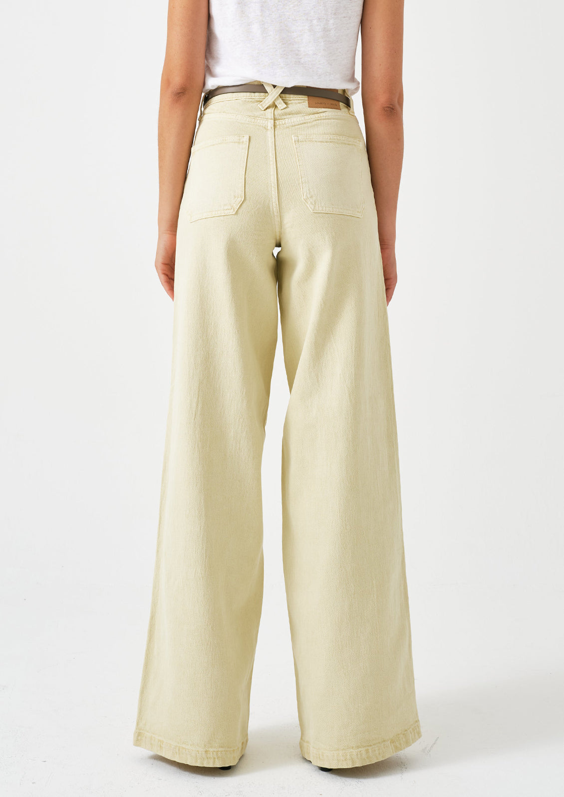 A person wearing a pair of long wide leg jeans in butter yellow color.