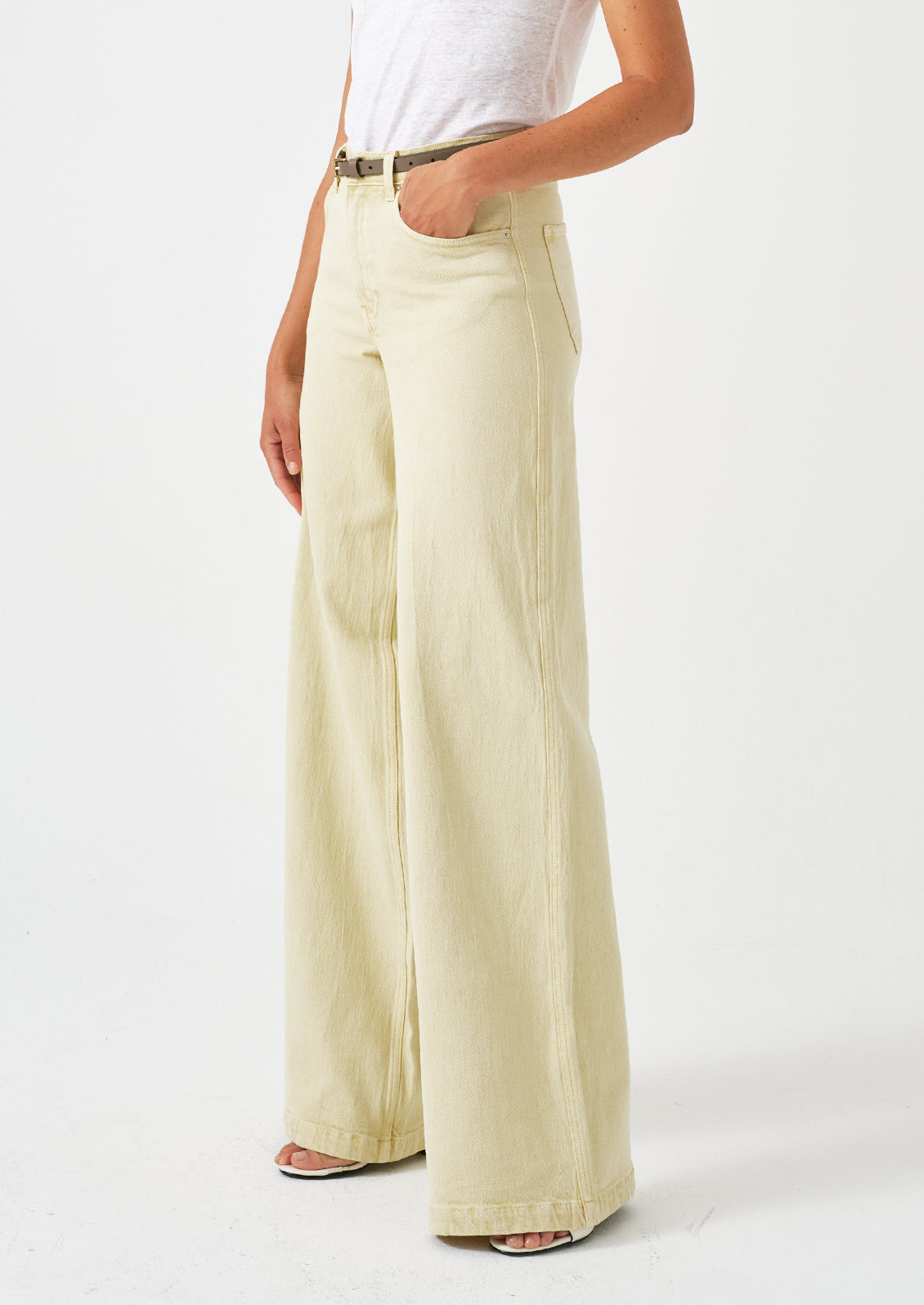 A person wearing a pair of long wide leg jeans in butter yellow color.