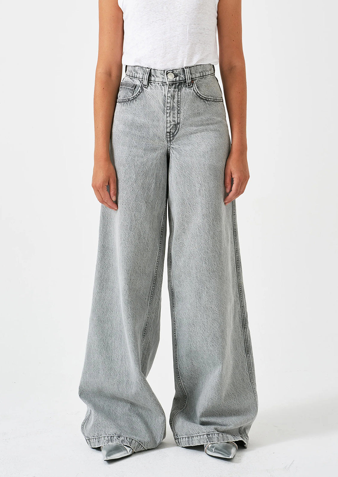 A person wearing a pair of wide leg baggy jeans in light grey denim.