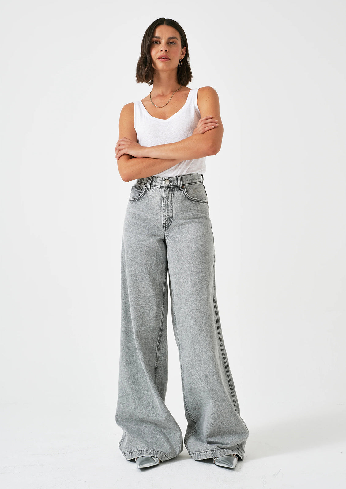A person wearing a pair of wide leg baggy jeans in light grey denim.
