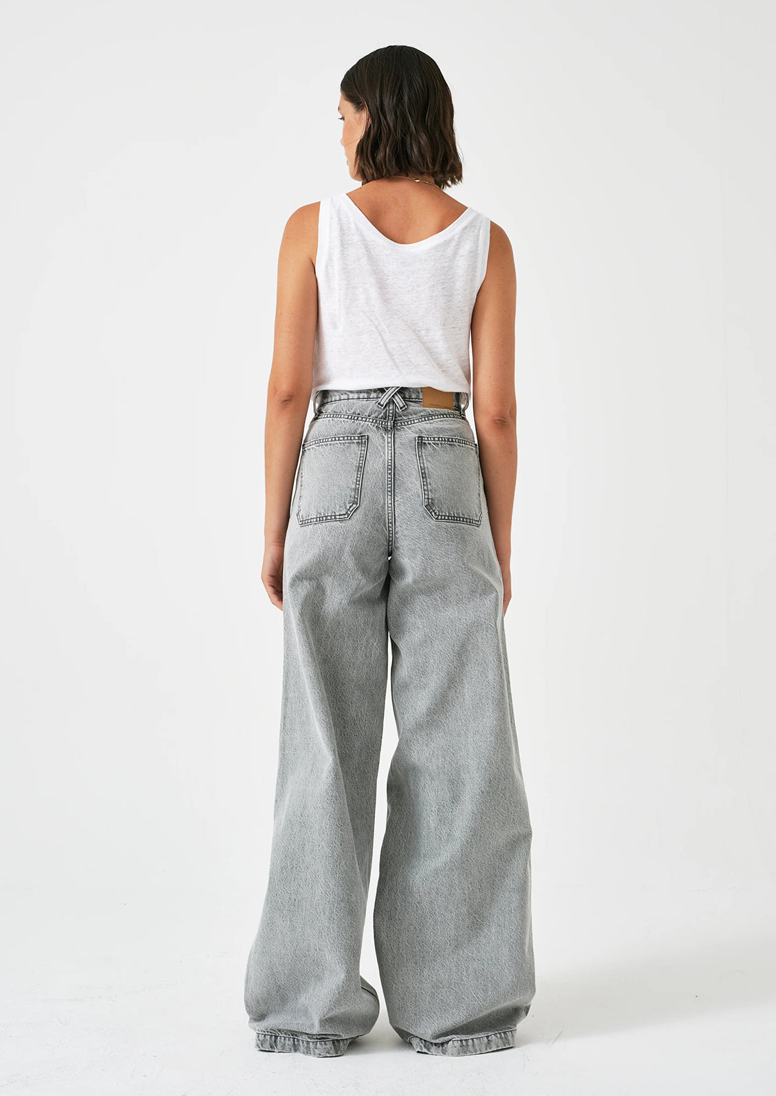 A person wearing a pair of wide leg baggy jeans in light grey denim.