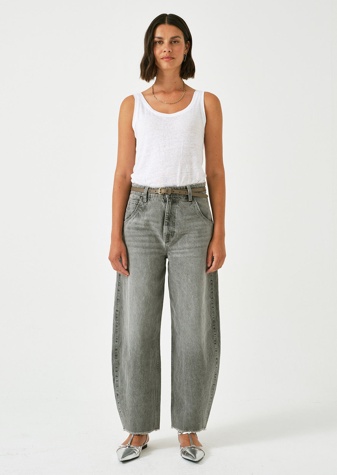 A woman wearing a pair of barrel leg jeans in grey wash.