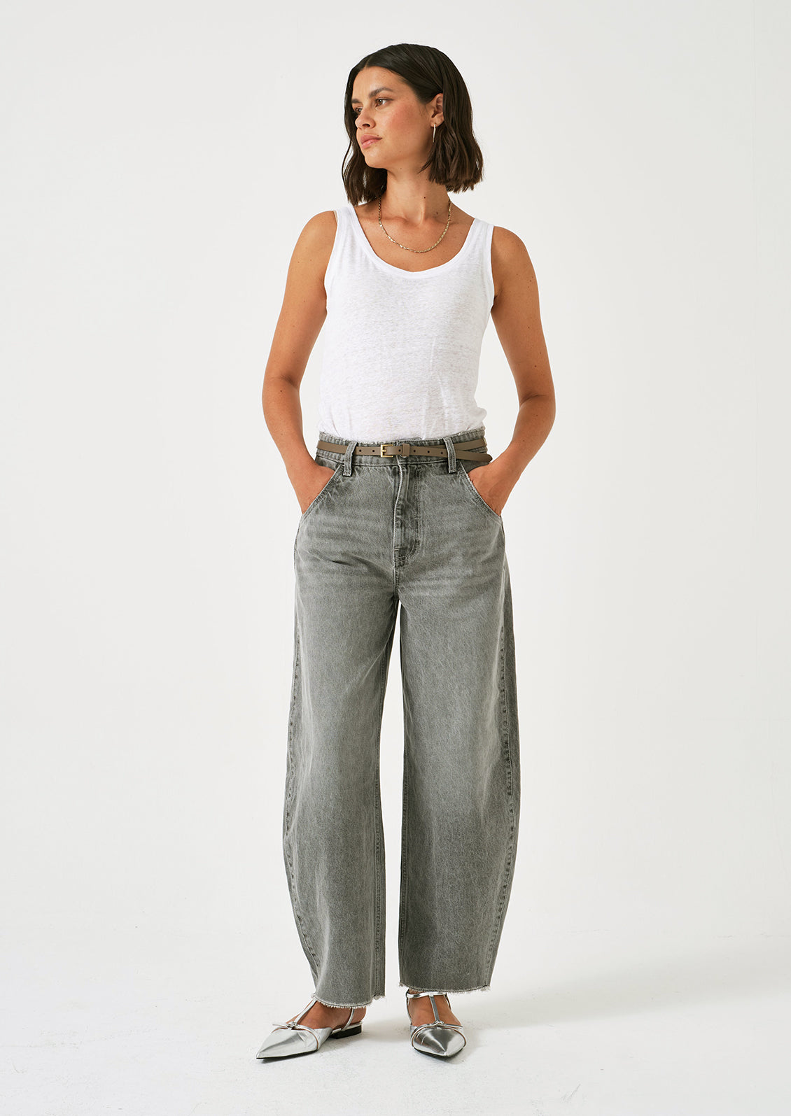 A woman wearing a pair of barrel leg jeans in grey wash.