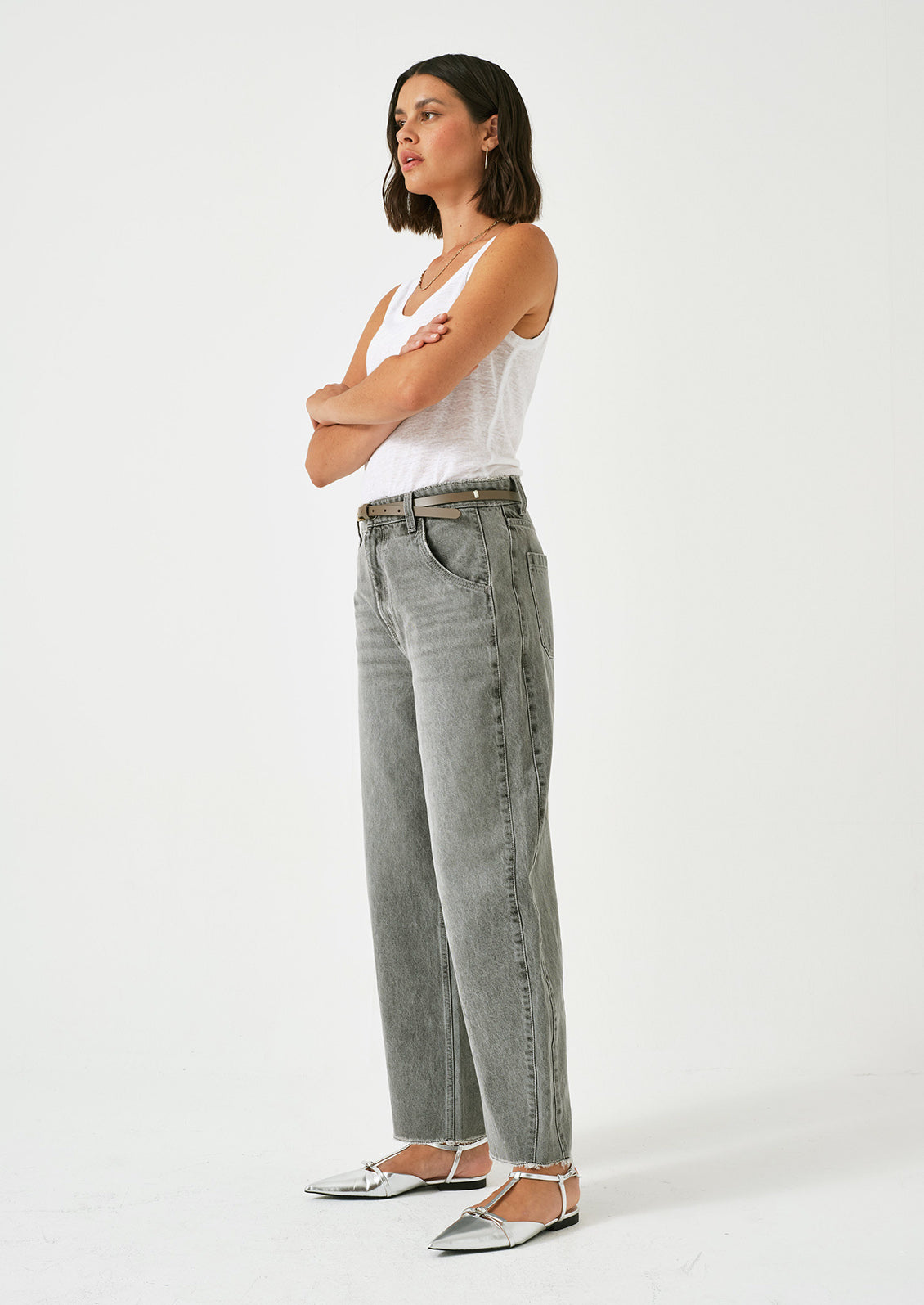 A woman wearing a pair of barrel leg jeans in grey wash.