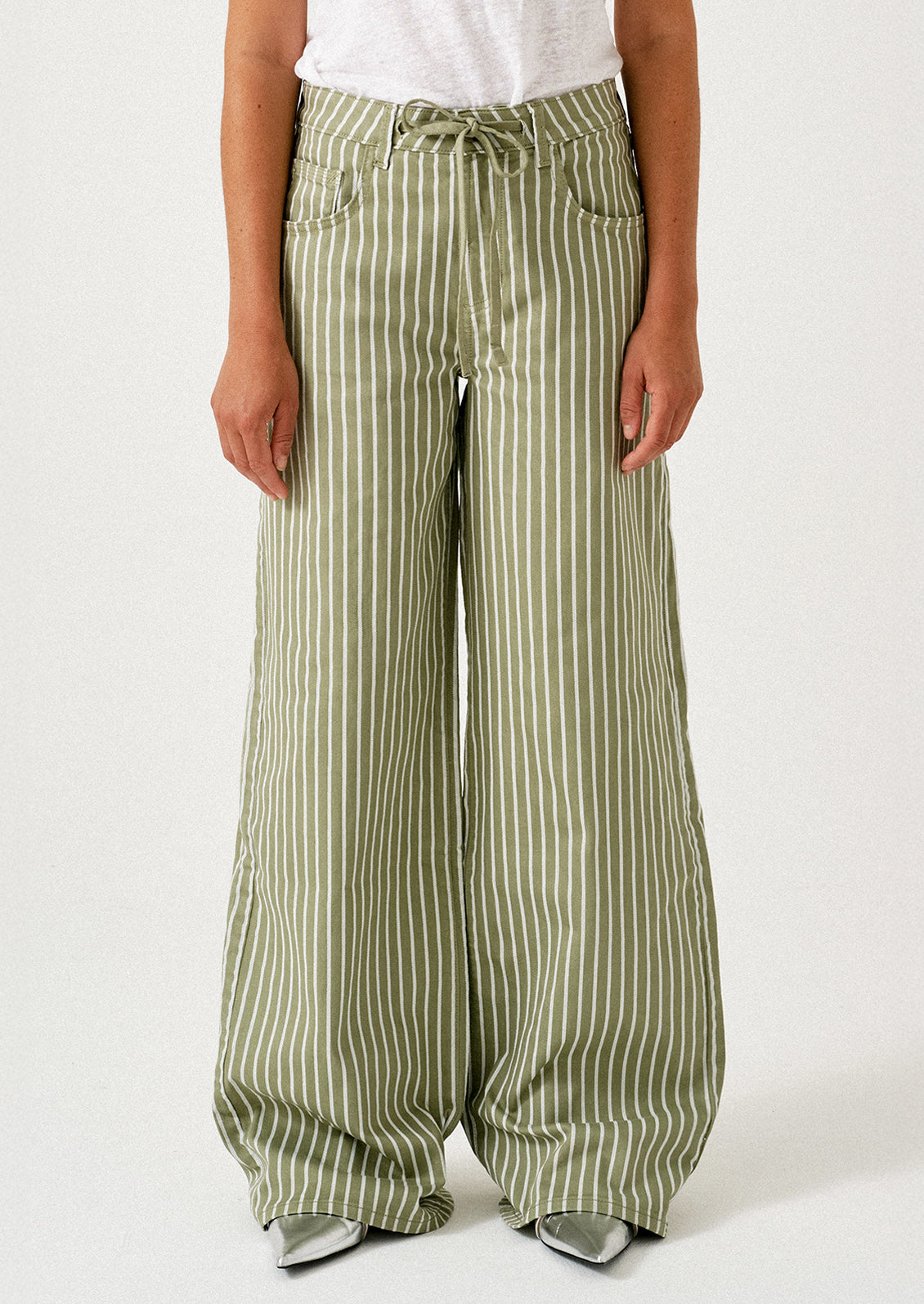 A woman wearing a pair of green jeans with white stripes and drawstring waist.