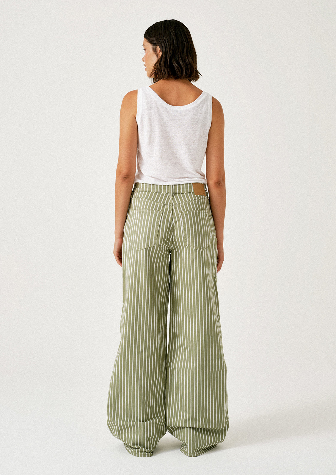 A woman wearing a pair of green jeans with white stripes and drawstring waist.