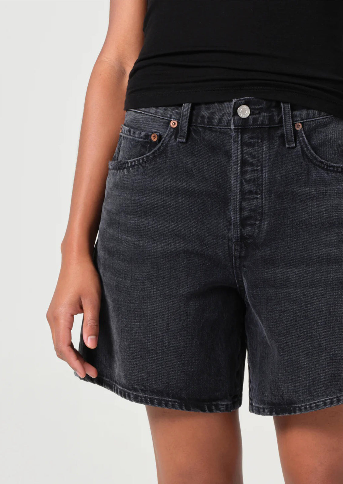 A person wearing a pair of relaxed denim shorts in dark grey wash.