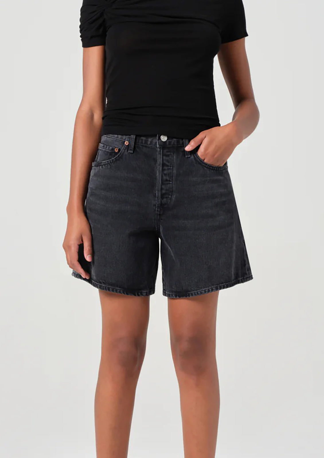 A person wearing a pair of relaxed denim shorts in dark grey wash.
