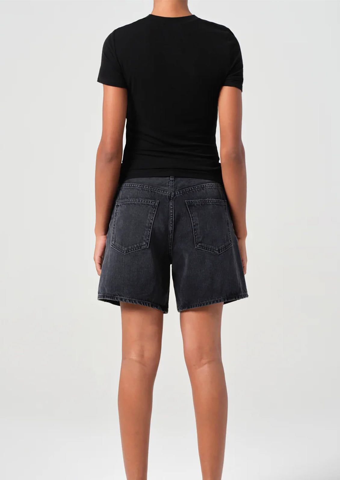 A person wearing a pair of relaxed denim shorts in dark grey wash.