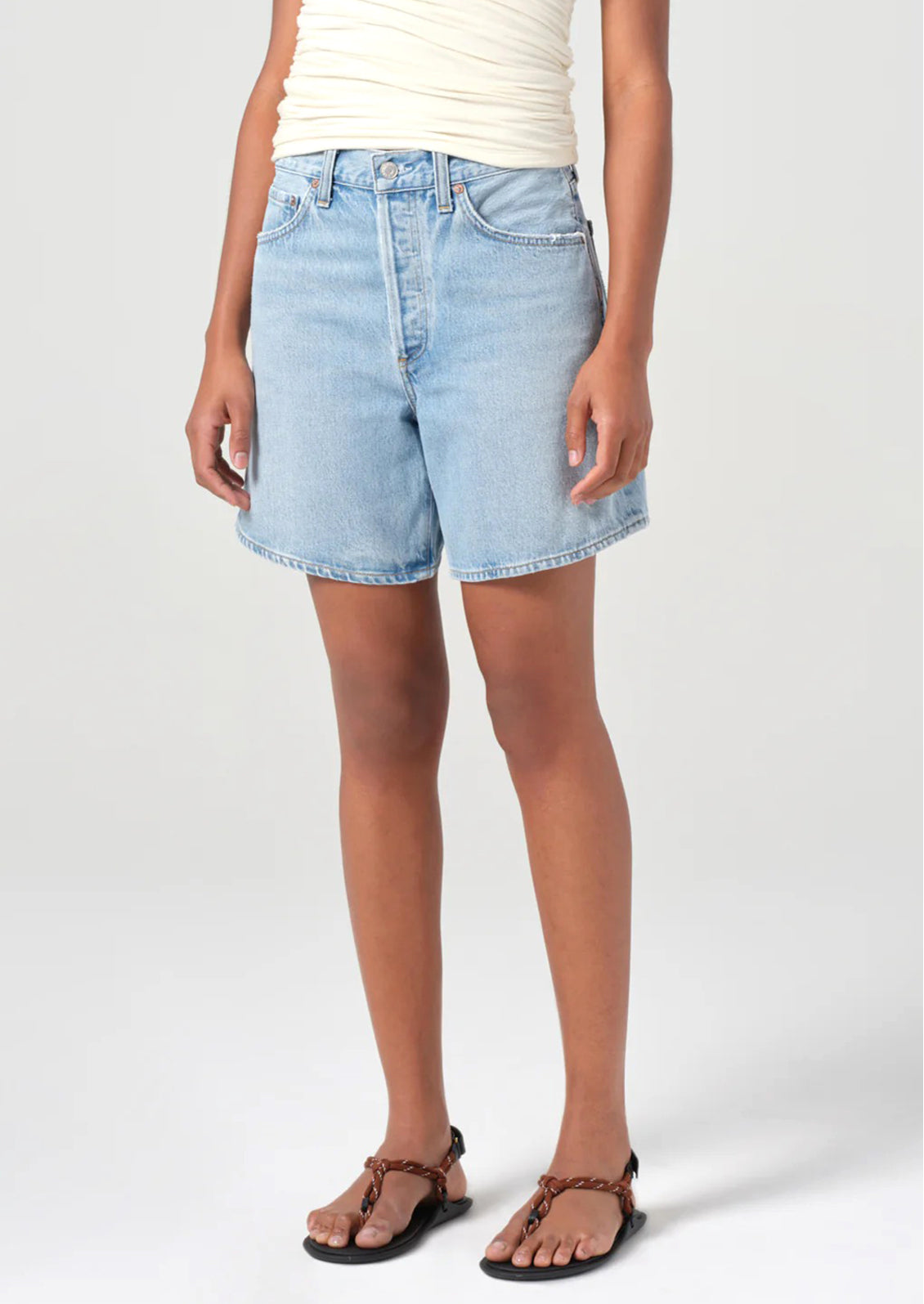 A person wearing a pair of relaxed denim shorts in light wash.