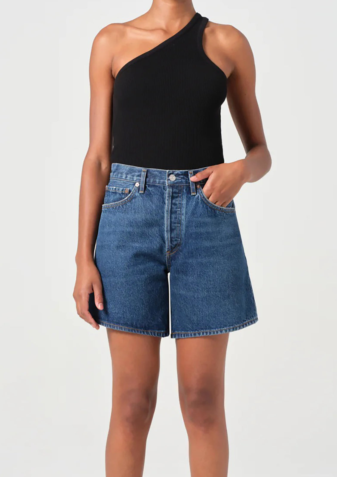 A person wearing a pair of relaxed denim shorts in dark blue wash.