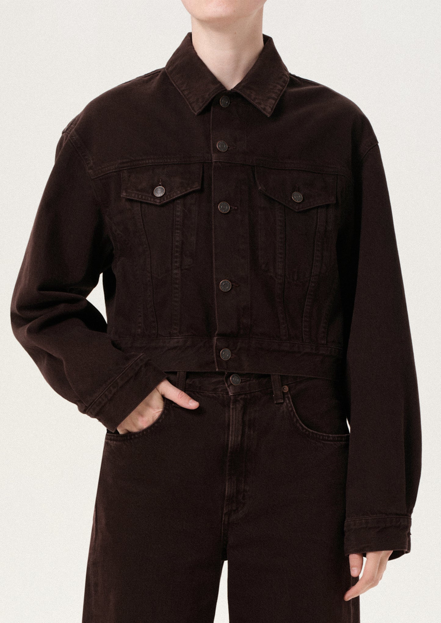 Person wearing a brown jacket and pants on a white background