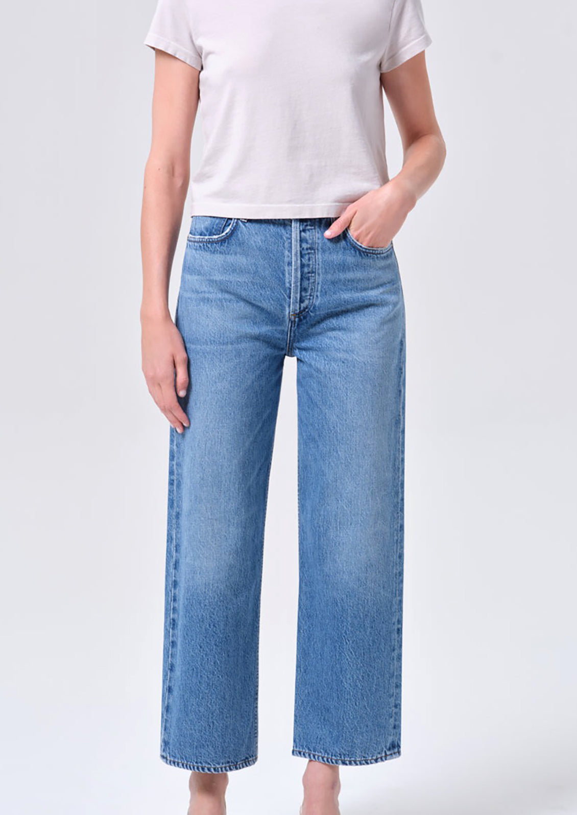 Person wearing blue jeans and a white t-shirt on a light gray background