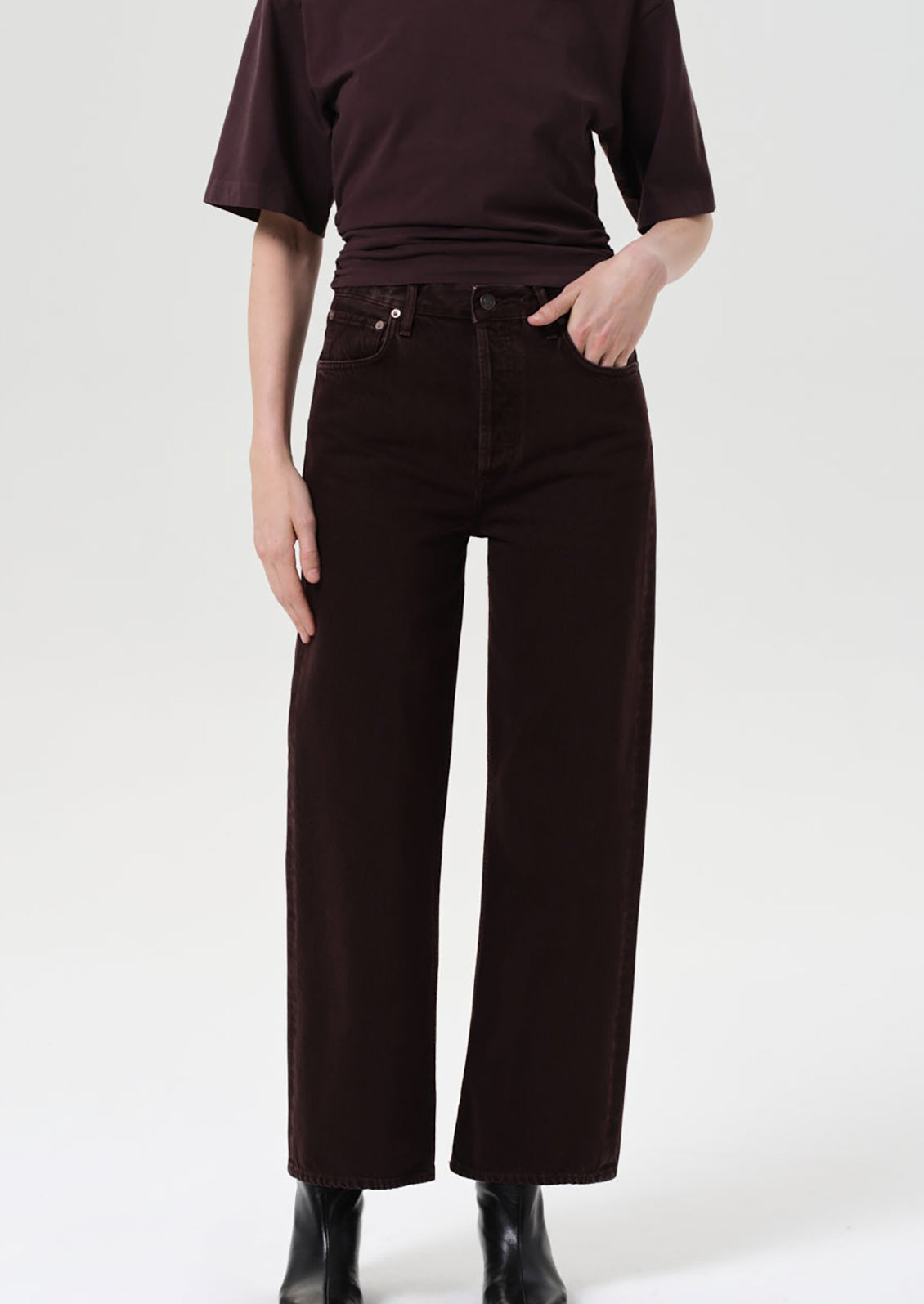 Person wearing a dark brown top and wide-leg pants on a white background