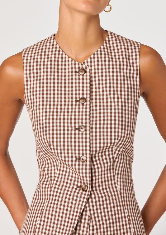 A person wearing a sleeveless button front vest in brown and white gingham.
