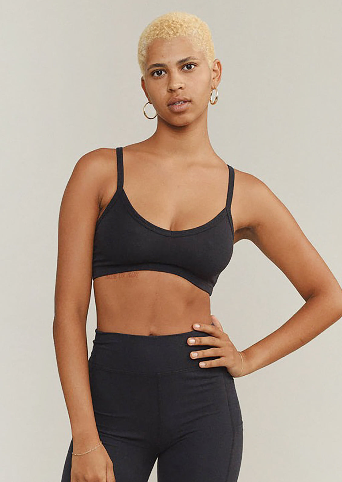 Woman wearing a black sports bra and leggings against a neutral background