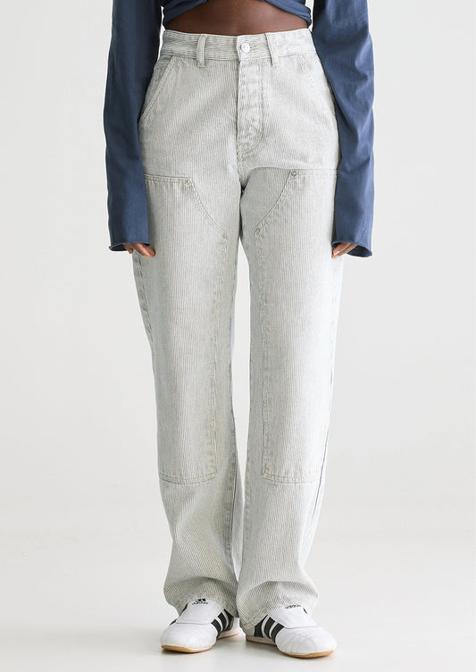 A woman wearing a pair of carpenter-style jeans in thin black pinstripe.