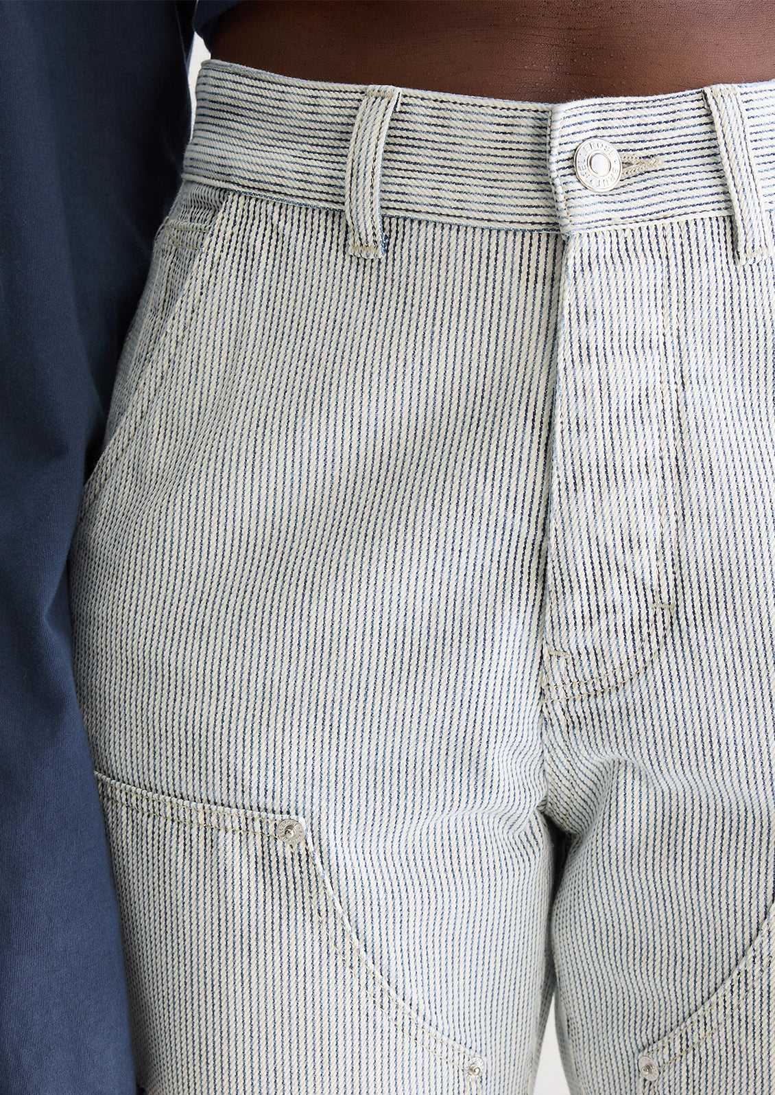 A woman wearing a pair of carpenter-style jeans in thin black pinstripe.