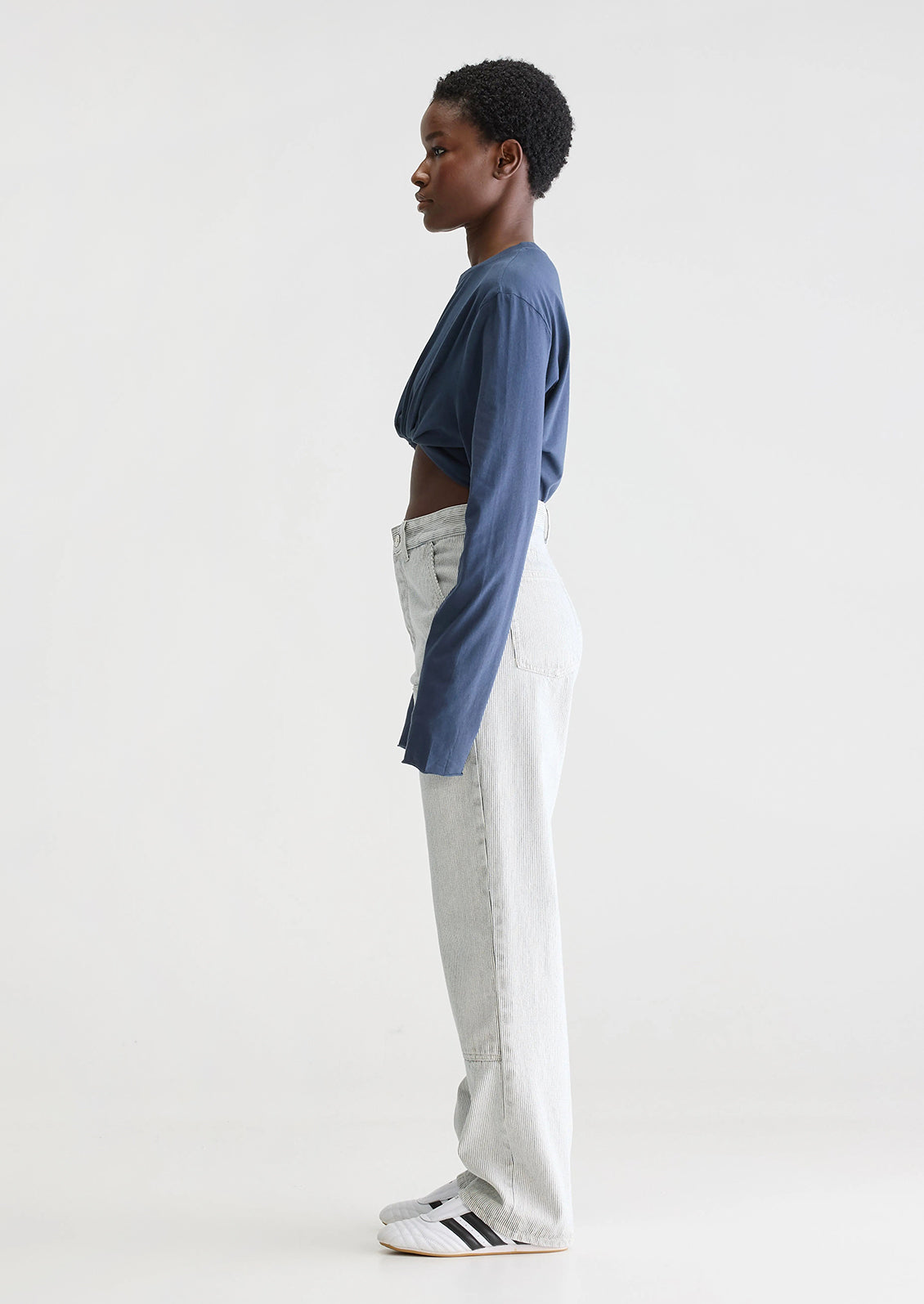 A woman wearing a pair of carpenter-style jeans in thin black pinstripe.