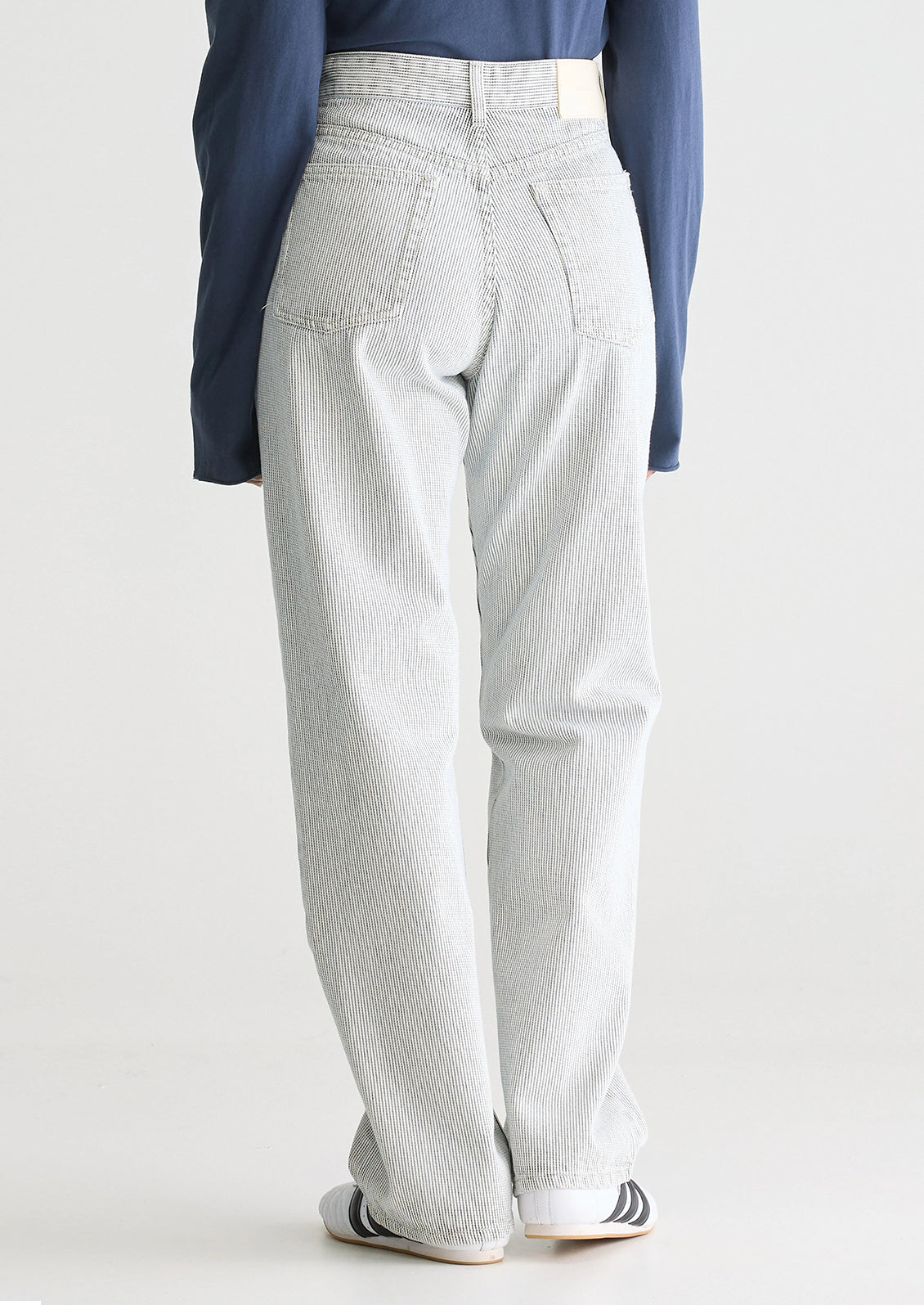 A woman wearing a pair of carpenter-style jeans in thin black pinstripe.