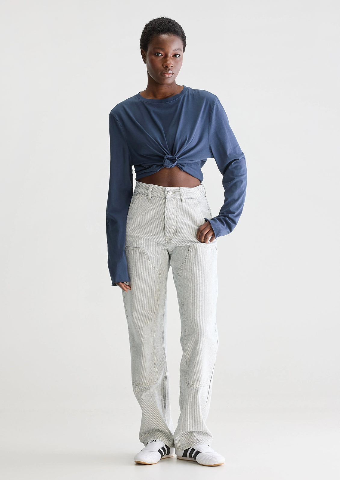 A woman wearing a pair of carpenter-style jeans in thin black pinstripe.