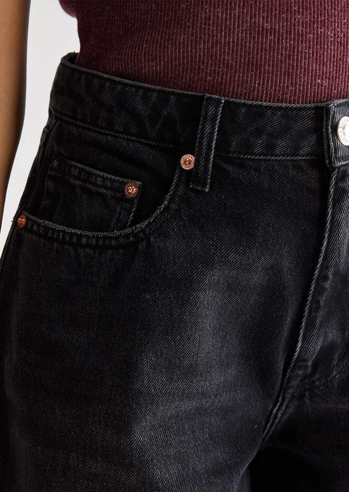 A person wearing a pair of wide leg denim shorts in charcoal wash.