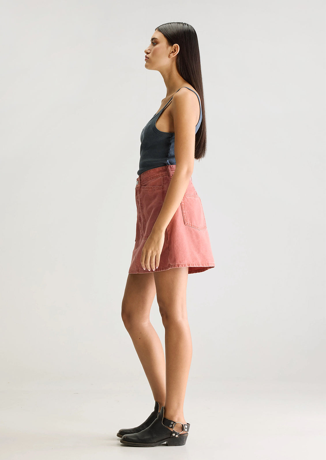 A person wearing a mini skirt in coral colored denim.