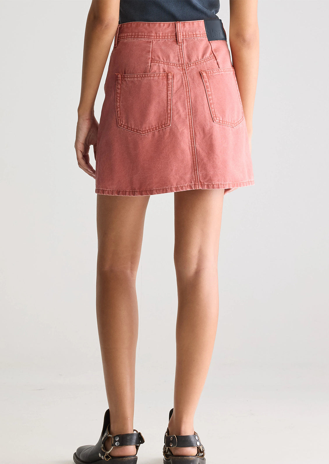 A person wearing a mini skirt in coral colored denim.