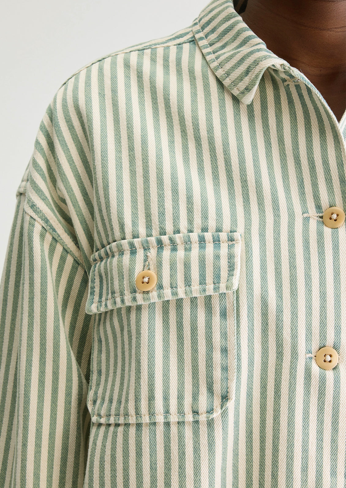 A woman wearing a striped overshirt in cream and acid dye blue/gree