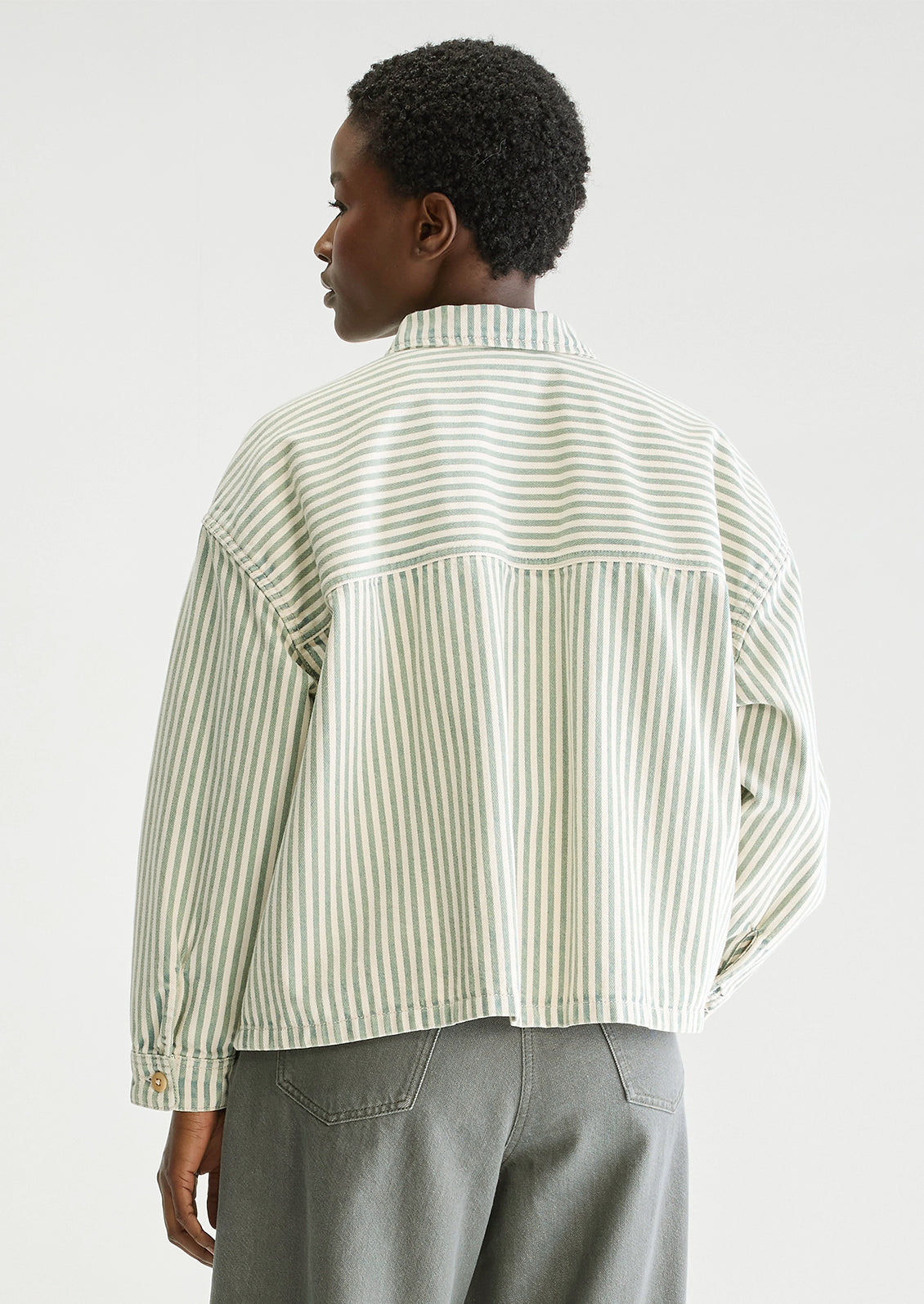 A woman wearing a striped overshirt in cream and acid dye blue/green.