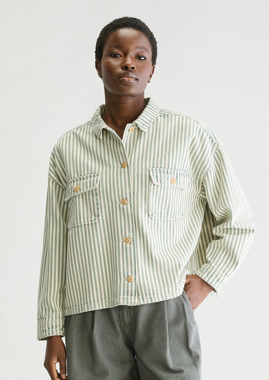 A woman wearing a striped overshirt in cream and acid dye blue/green.