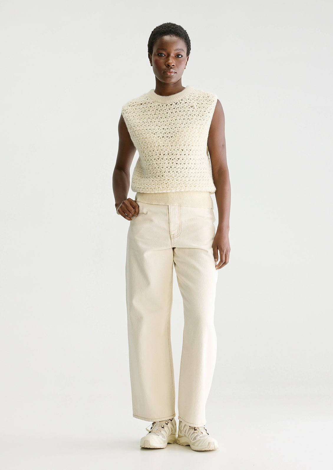 A woman wearing a sleeveless crewneck sweater vest in triangular open weave wool.