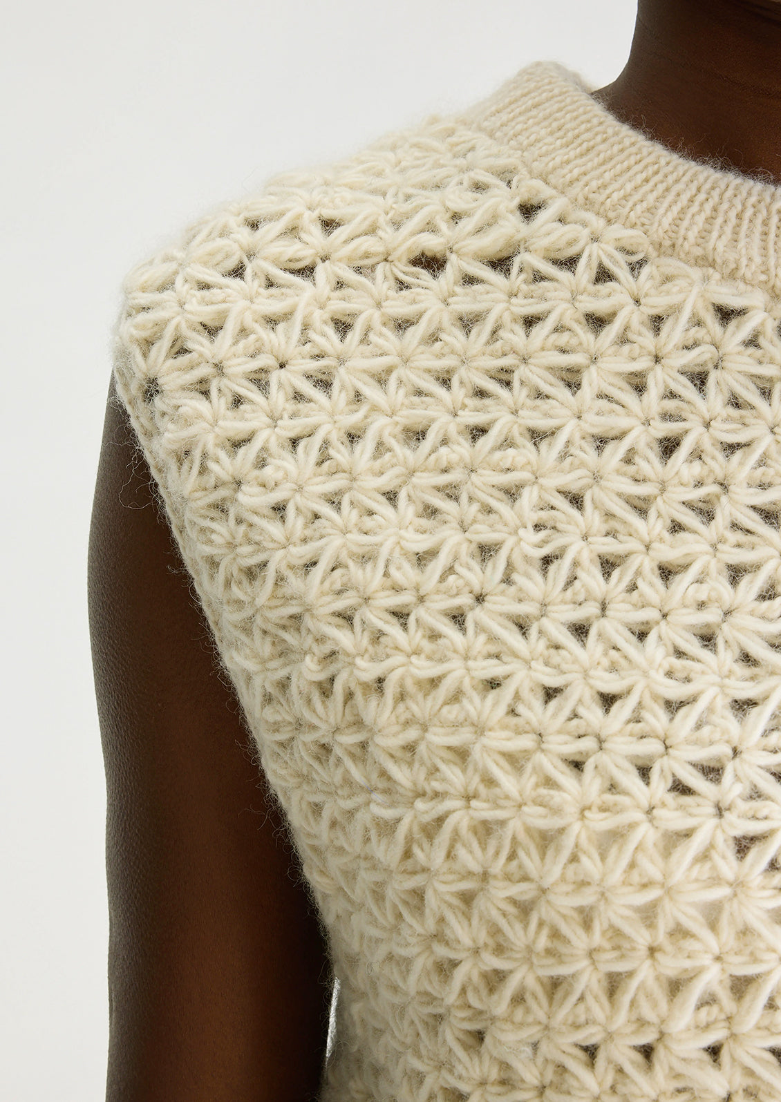 A woman wearing a sleeveless crewneck sweater vest in triangular open weave wool.